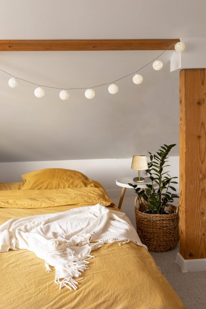 dormitorio con guirnalda de luces y lampara sobremesa