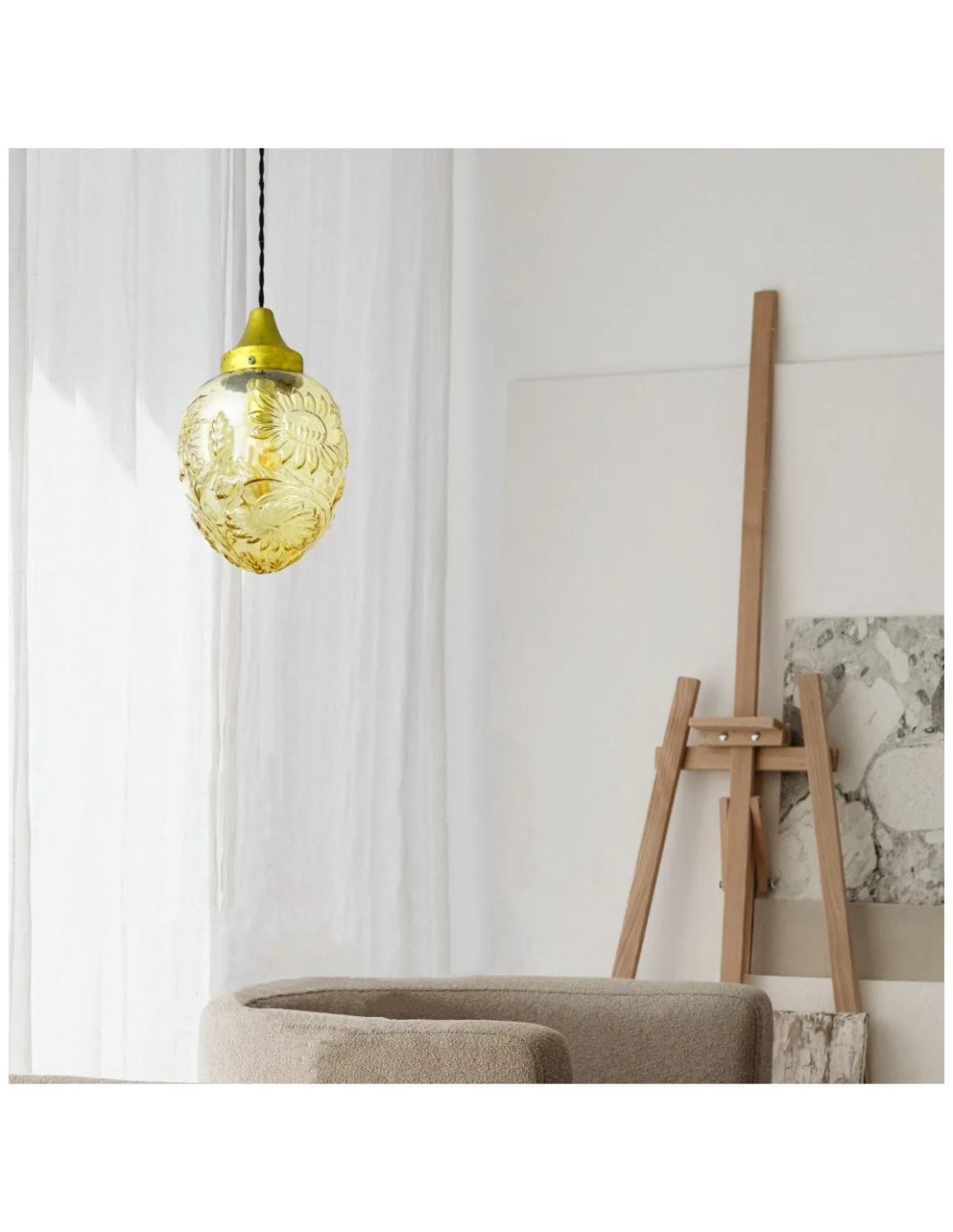 Lámpara colgante de cristal ámbar con motivos florales grabados, suspendida en un espacio interior luminoso y elegante.