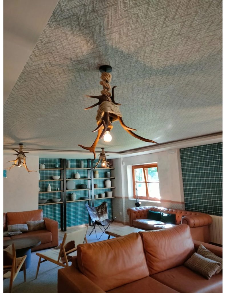 Salón rústico con lámparas de techo artesanales de cuernos de ciervo, luz cálida y mobiliario acogedor de estilo natural.