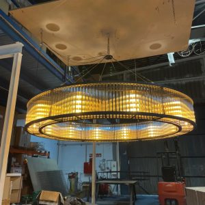 Lámpara colgante circular grande con diseño industrial y luz cálida tipo vintage en proceso de instalación