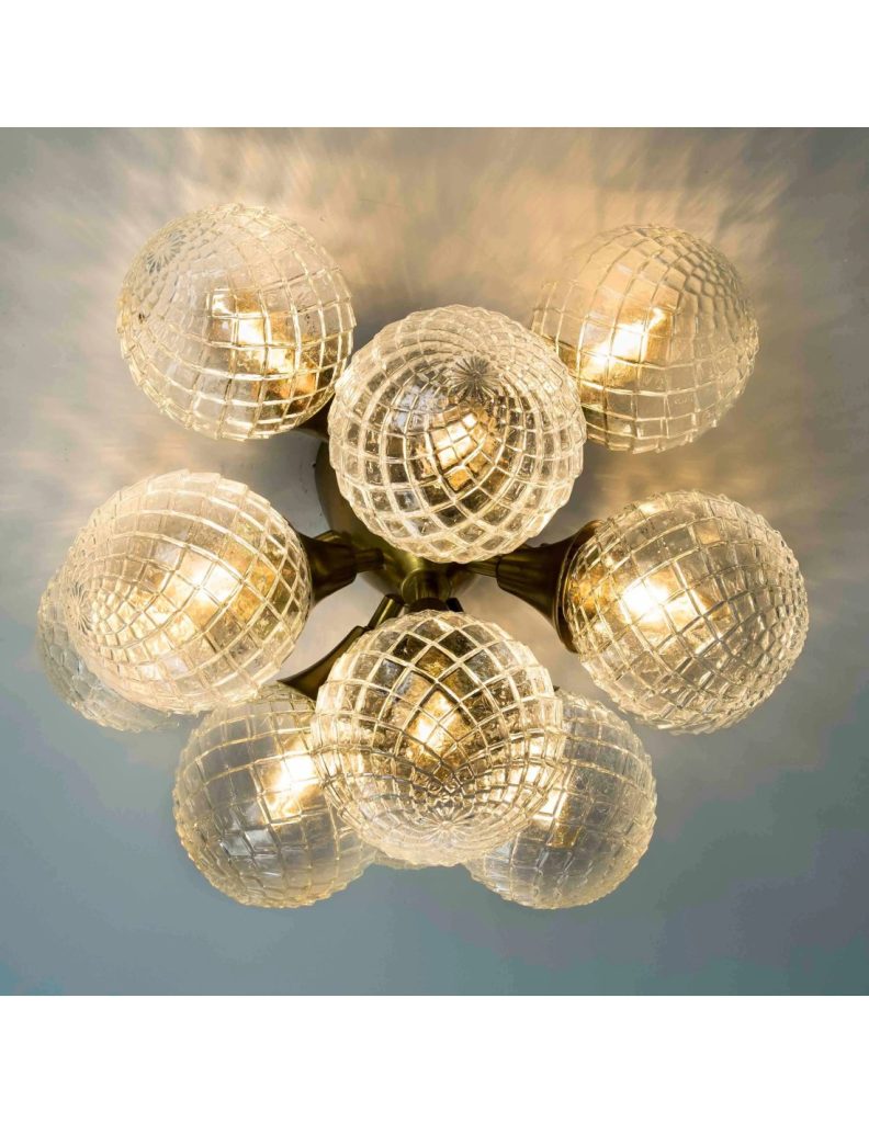 Plafón de techo vintage con estructura en latón envejecido y tulipas esféricas de cristal texturizado que emiten una luz cálida.
