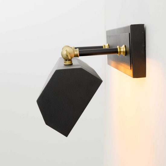 Aplique de pared orientable con pantalla geométrica en negro mate y detalles en latón.
