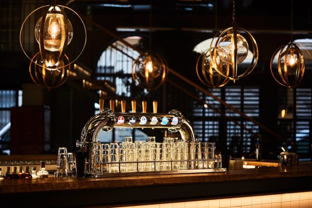 Lámparas colgantes decorativas de estilo industrial con esferas metálicas doradas en un bar contemporáneo.