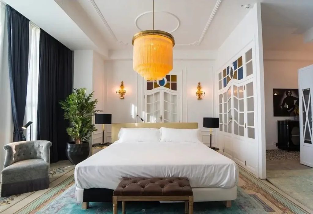 Dormitorio elegante con lámpara colgante de flecos iluminando un espacio clásico y sofisticado.