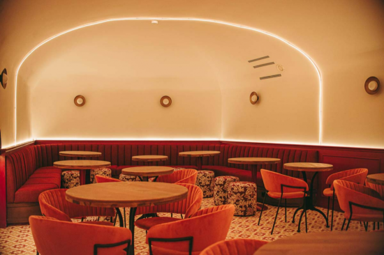 Espacio de restauración con iluminación cálida indirecta y apliques circulares de estilo contemporáneo.