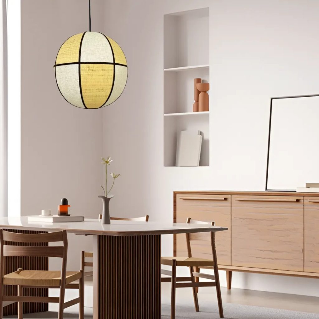 Comedor moderno con lámpara colgante de pantalla textil geométrica, mesa de madera y mobiliario minimalista.