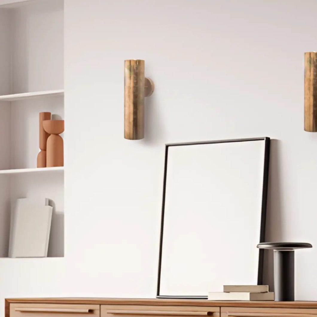 Aplique de pared cilíndrico en acabado latón envejecido instalado en un salón de estilo minimalista.