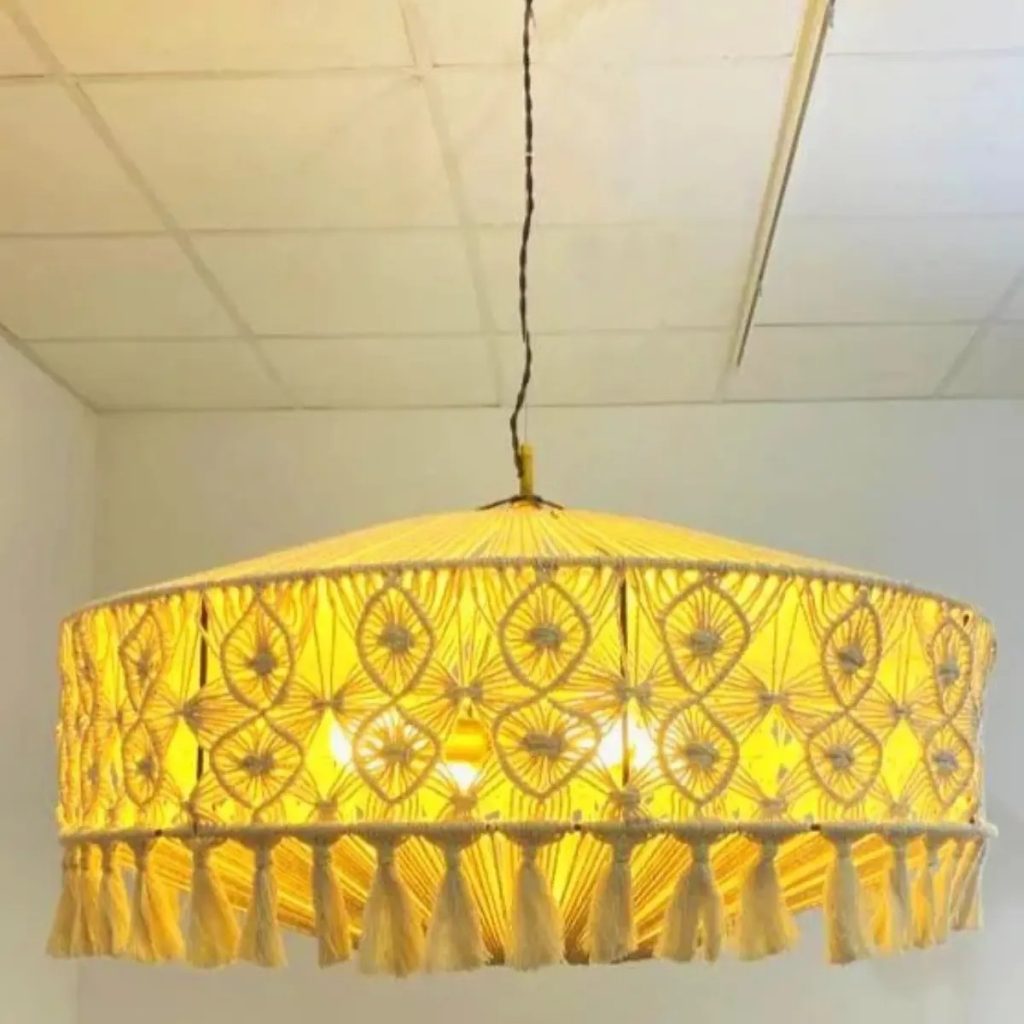 Lámpara colgante artesanal de macramé con flecos decorativos y luz cálida de estilo boho natural.