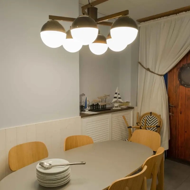 Lámpara de techo con múltiples globos opal iluminando un comedor de estilo contemporáneo.