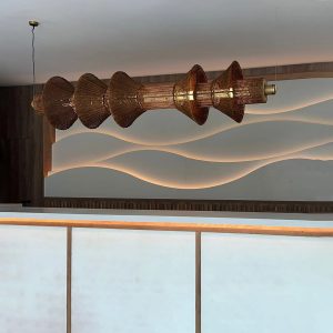 Lámpara colgante escultórica de gran formato en fibra trenzada con diseño orgánico y ambiente cálido contemporáneo.
