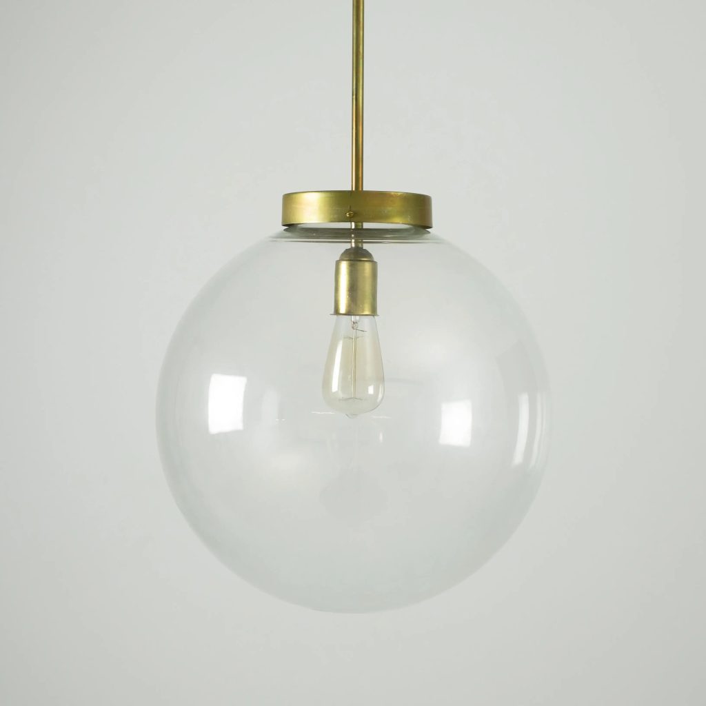 Lámpara colgante con esfera de cristal transparente y estructura en latón envejecido.