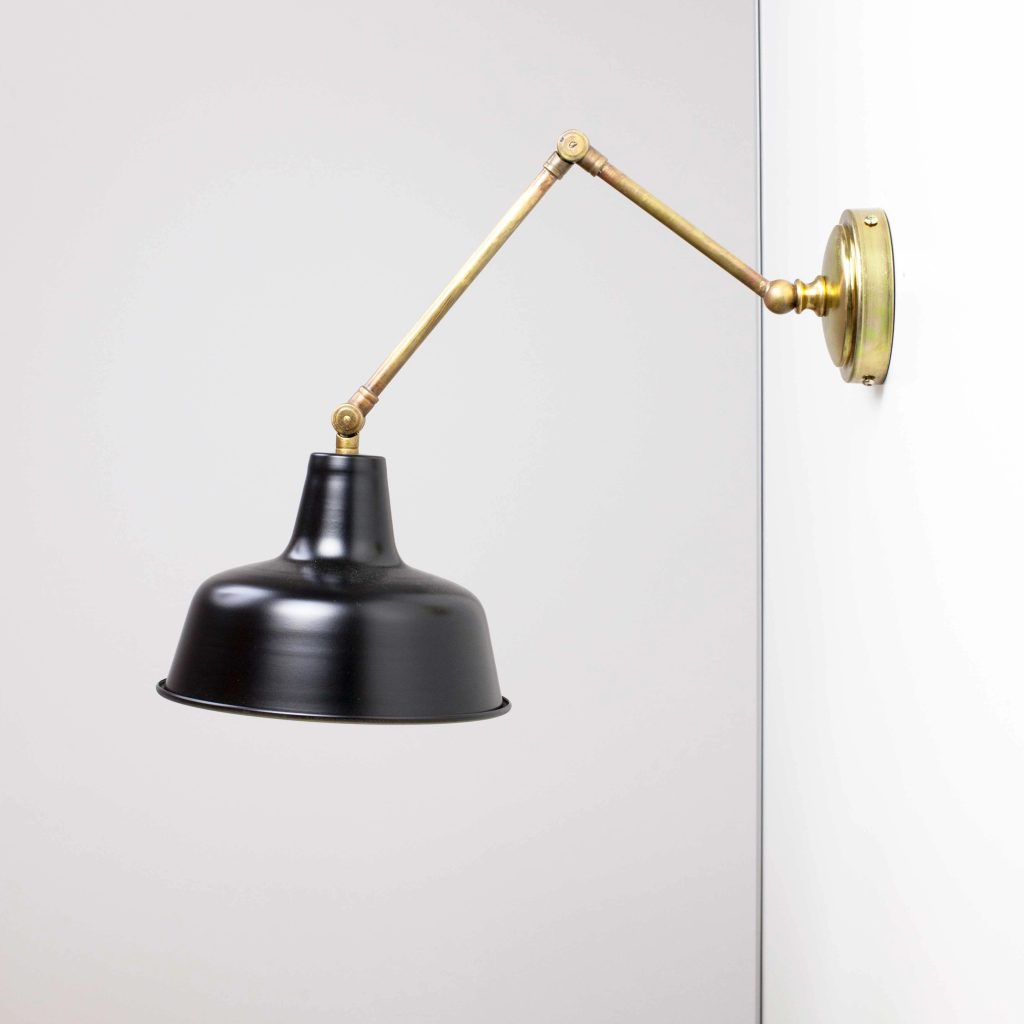 Aplique de pared articulado en latón con pantalla metálica negra de estilo vintage industrial.