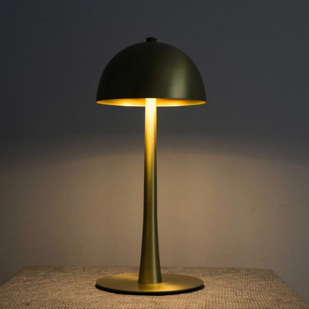 Lámpara de sobremesa vintage en acabado dorado oscuro con pantalla semiesférica e iluminación cálida.