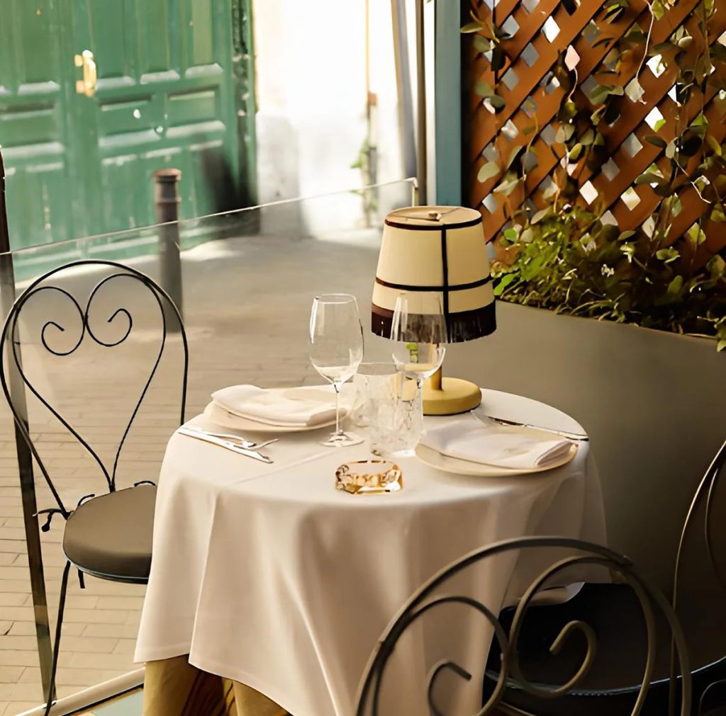 Lámpara de sobremesa vintage con pantalla beige y detalles negros sobre mesa de restaurante elegante.