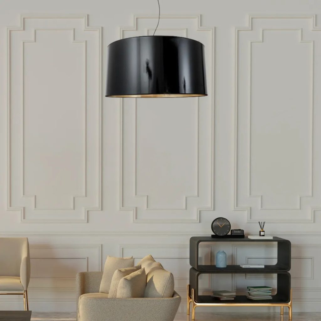 Lámpara colgante negra de pantalla cilíndrica en salón elegante con molduras clásicas y mobiliario contemporáneo.