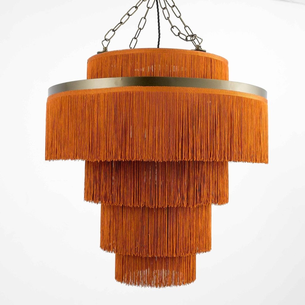 Lámpara colgante vintage con flecos naranjas en varios niveles y estructura metálica suspendida con cadena.