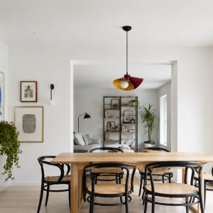 Lámpara colgante roja y dorada sobre mesa de comedor en interior moderno y luminoso