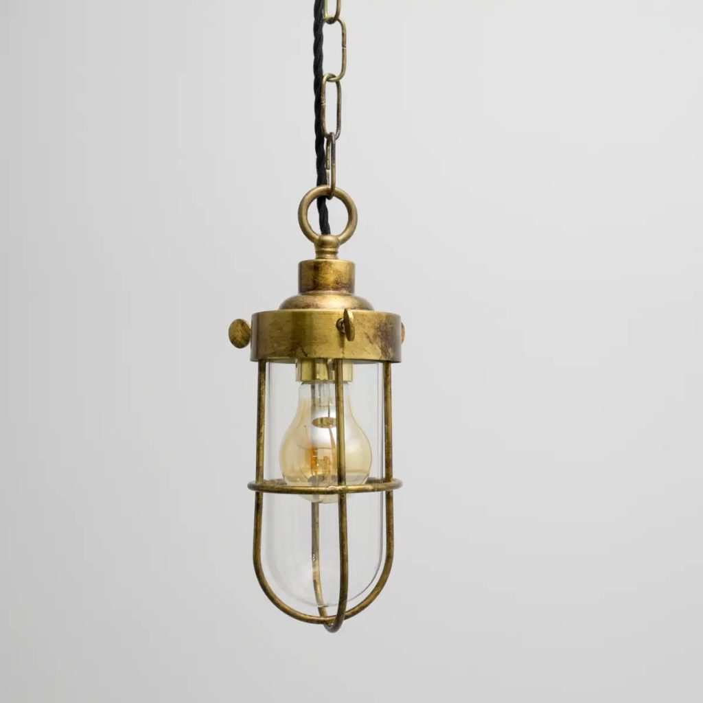 Lámpara colgante vintage tipo farol con estructura de latón envejecido, cristal transparente y bombilla vista sobre fondo claro