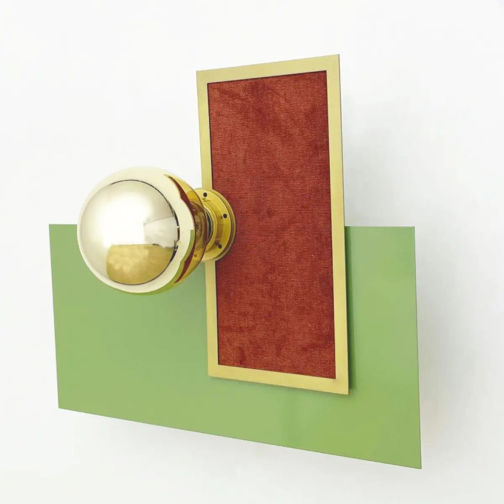 Aplique de pared decorativo con globo de cristal opal, estructura en latón y paneles geométricos en verde y rojo.