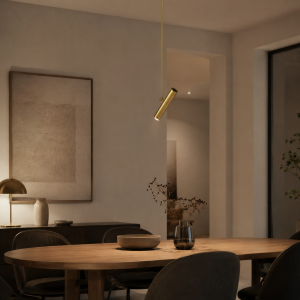 Lámpara colgante cilíndrica en latón instalada sobre mesa de comedor en interior moderno con luz cálida.