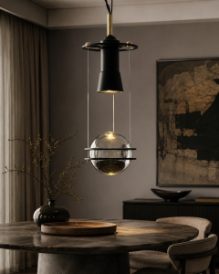 Lámpara colgante de diseño en metal negro y latón con esfera de cristal ahumado instalada sobre mesa de comedor elegante.