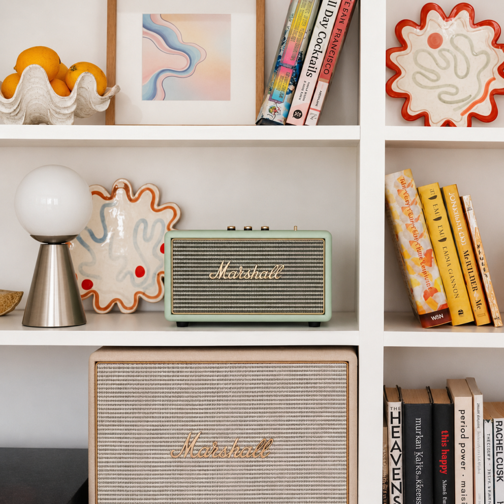 Lámpara de sobremesa con globo opal y base metálica sobre una estantería decorativa