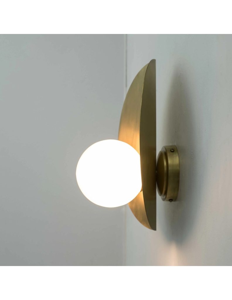 Aplique de pared en acabado latón envejecido con globo blanco iluminado sobre pared clara