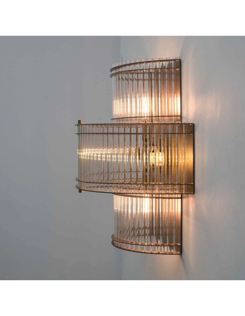 Aplique de pared vintage de tres niveles con varillas de cristal transparente, estructura dorada y luz cálida.