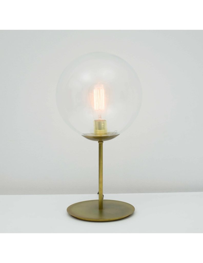 Lámpara de mesa vintage con base dorada, bola de cristal transparente y bombilla vista sobre fondo blanco