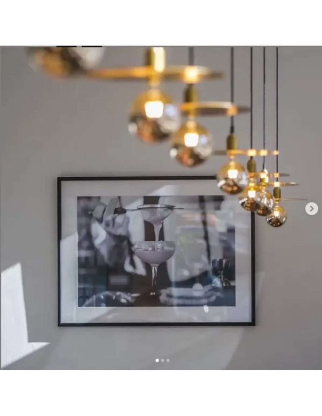 Lámpara vintage de techo con discos dorados y globos de cristal ahumado, suspendida mediante cables negros.
