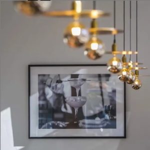 Lámpara vintage de techo con discos dorados y globos de cristal ahumado, suspendida mediante cables negros.