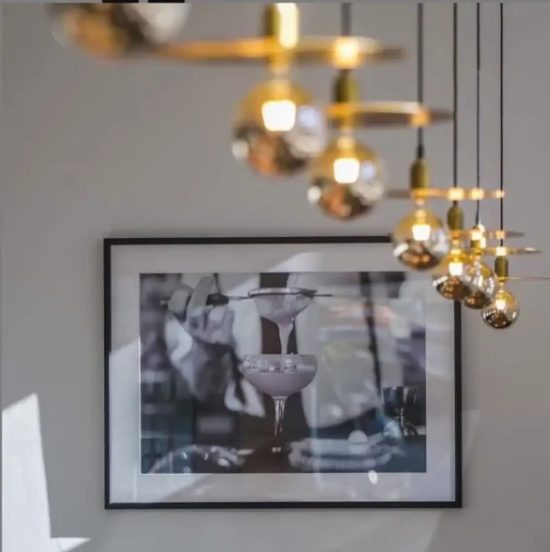 Lámpara vintage de techo con discos dorados y globos de cristal ahumado, suspendida mediante cables negros.