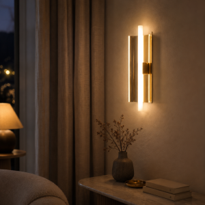 Aplique de pared vertical de latón con luz cálida junto a una consola en un dormitorio elegante.