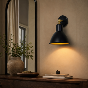 Aplique de pared negro con detalles de latón iluminando una consola de madera junto a un espejo.