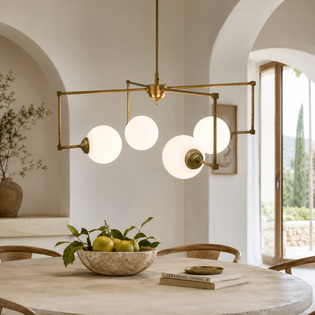 Lámpara colgante geométrica de latón con cinco globos de cristal opal sobre una mesa de comedor.