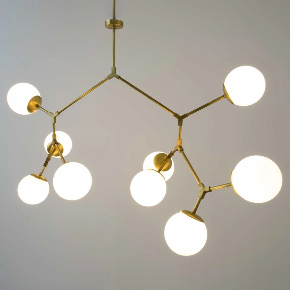 Lámpara colgante dorada de estilo vintage con estructura ramificada y globos de cristal opal iluminados.